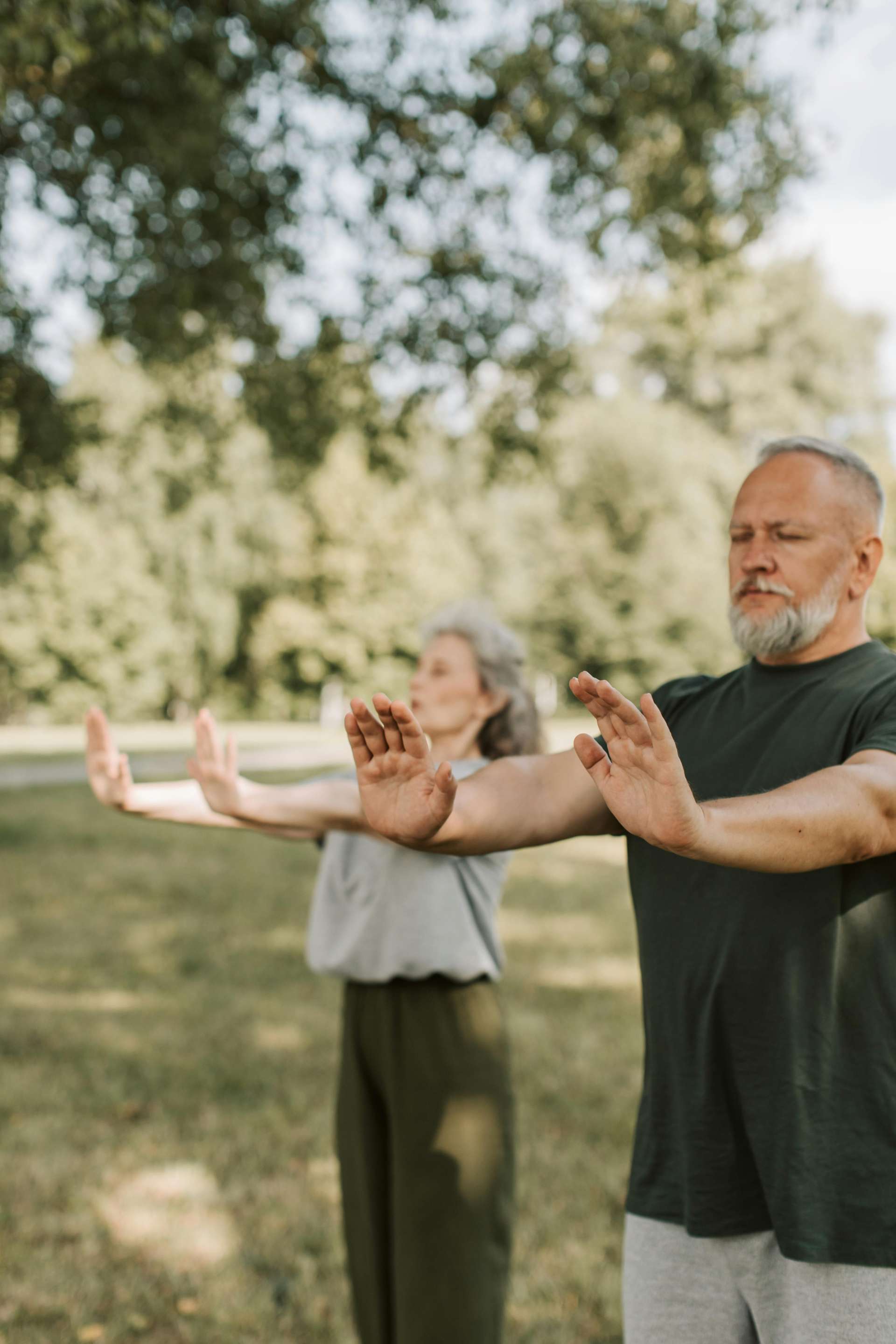 People practicing tai chi in a field surrounded by trees